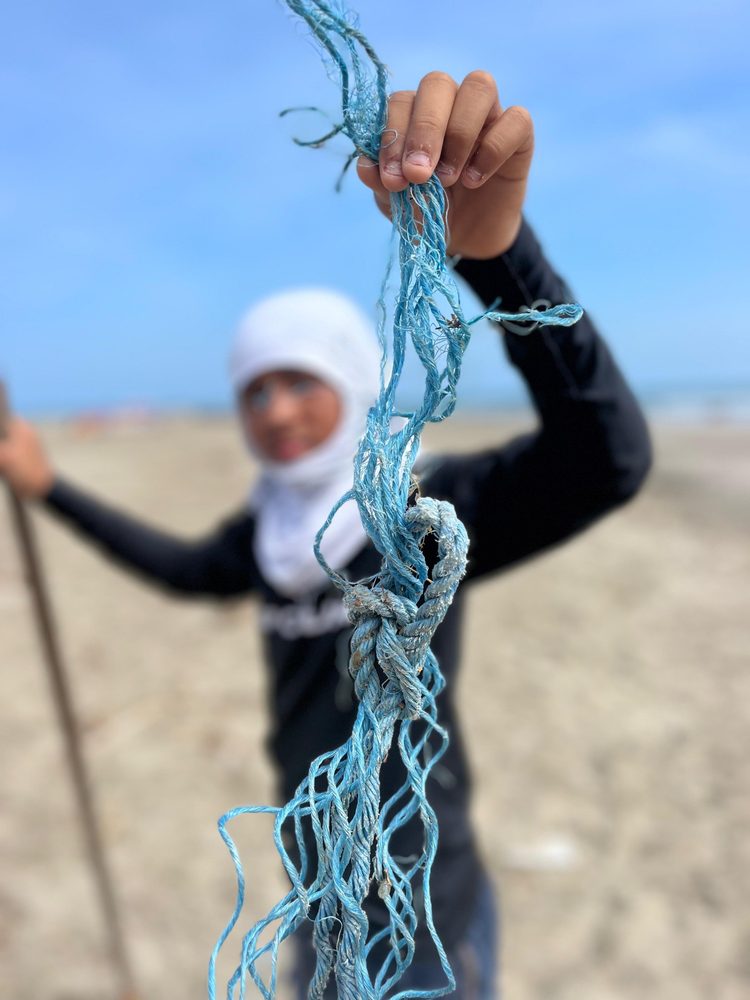 Niño sosteniendo una cuerda de plástico azul encontrada en la playa