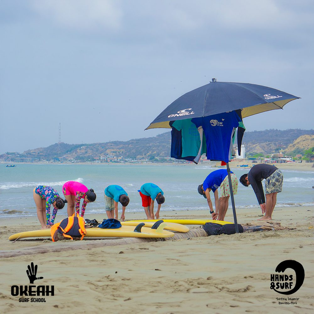 Niños haciendo estiramientos en la playa antes de la clase de surf