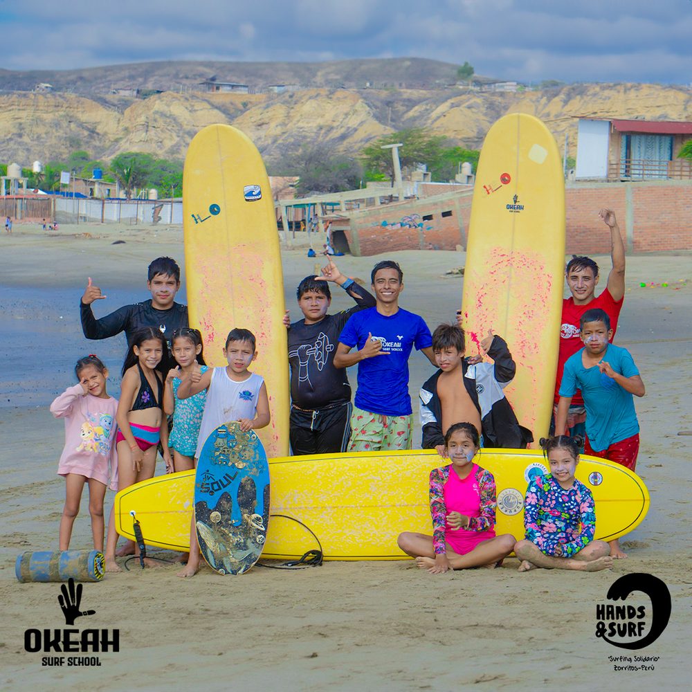 Grupo de niños y jóvenes posando con tablas de surf en la playa